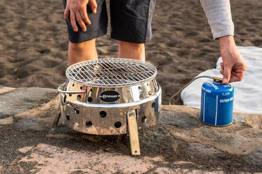 Eine Person zündet einen Atago-Gasgrill am Strand an