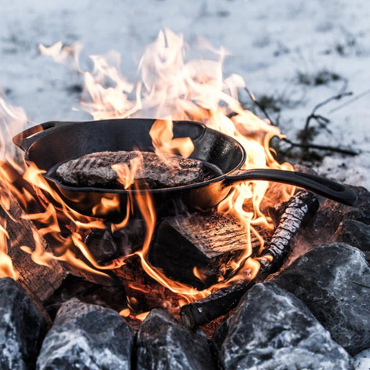 gegrilltes Fleisch in einer Feuerpfanne direkt über den Flammen des Feuers