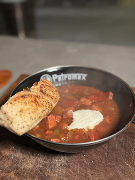 Herzhafte DDR Soljanka aus dem Dutch Oven mit Wurst, Fleisch, Paprika und Gewürzgurken in würziger Tomatensauce, direkt vom Grill serviert