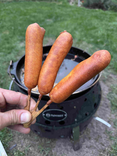 Goldbraun frittierte Corn Dogs mit Würstchen und geschmolzenem Käse auf Holzspießen.